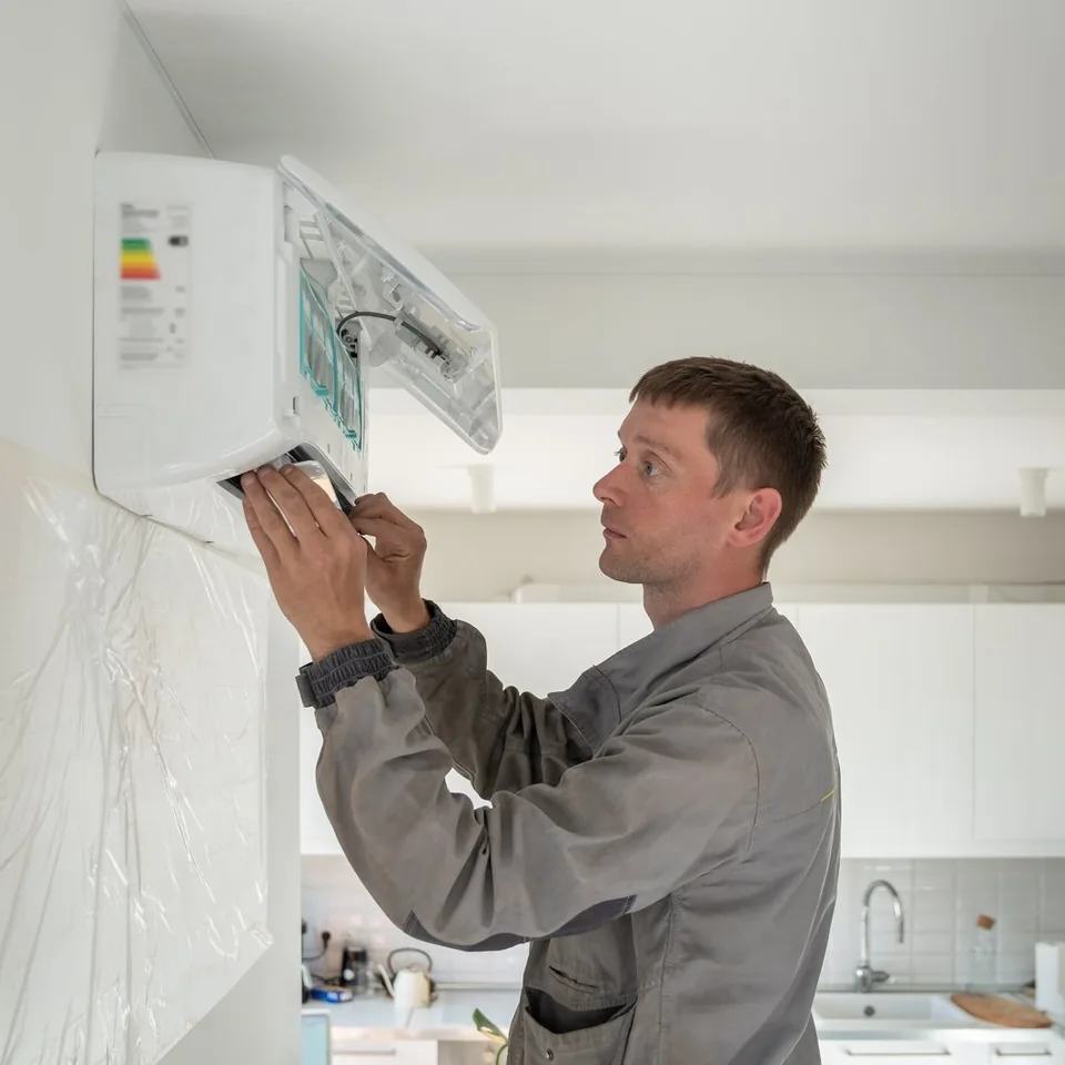 Technicien ajustant une unité de climatisation murale dans un logement