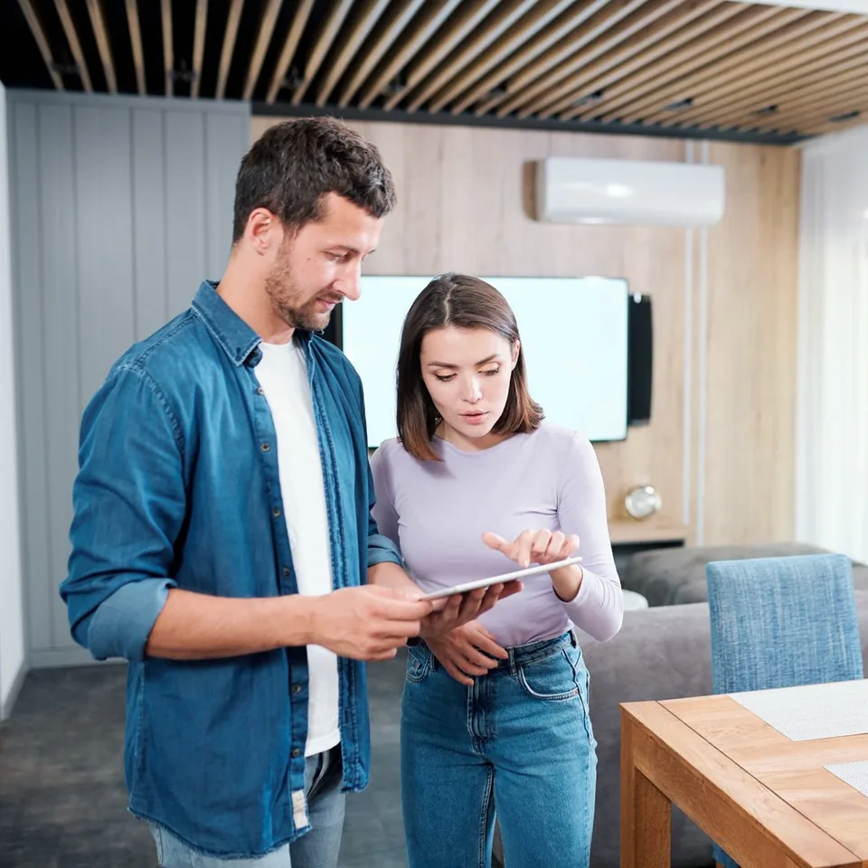 Couple échangeant autour d’une tablette dans un logement climatisé