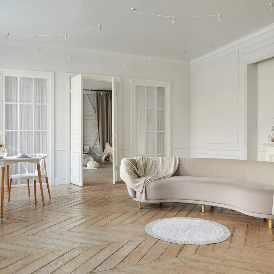 Séjour lumineux avec parquet à chevrons, murs blancs et espace repas